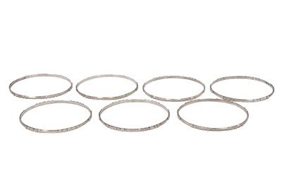Lot 24 - SEVEN INCISED SILVER BANGLES WITH GEOMETRIC MOTIFS