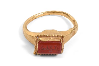 Lot 32 - AN ISLAMIC CARNELIAN-SET GOLD RING